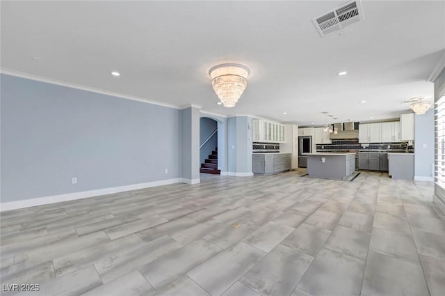 unfurnished living room featuring ornamental molding, recessed lighting, stairway, baseboards, and a sink