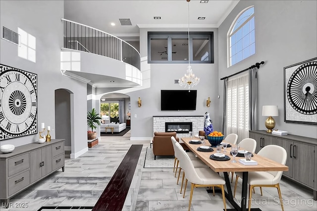 281 Powerbilt Ave, Las Vegas, NV 89148 - dining area with a towering ceiling, arched walkways, a stone fireplace, baseboards, and ornamental molding