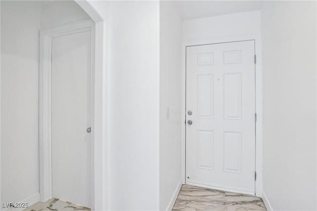 hallway with light marble finish floors, baseboards, and arched walkways