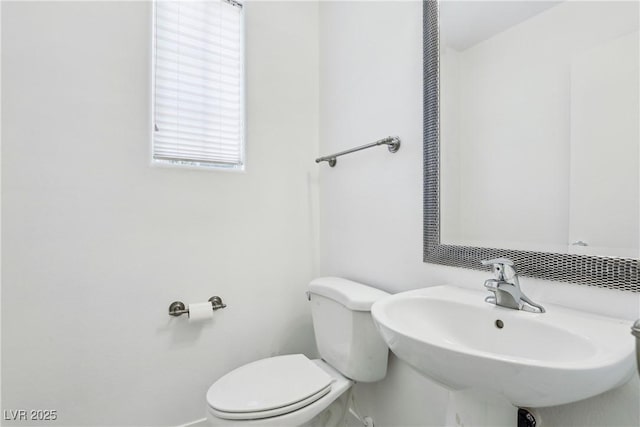 bathroom featuring toilet, a sink, and baseboards