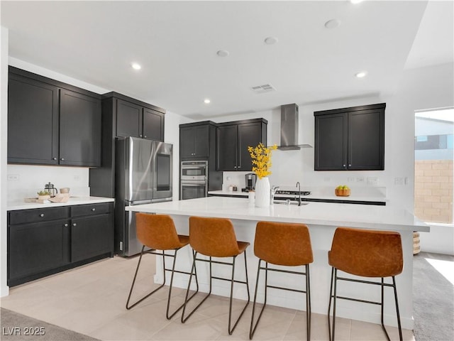 4246 W Landberg Ave, Las Vegas, NV 89141 - kitchen with wall chimney exhaust hood, stainless steel appliances, dark cabinets, light countertops, and a breakfast bar