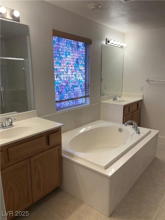 full bath with tile patterned flooring, a garden tub, two vanities, and a stall shower