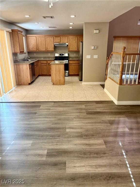 kitchen featuring appliances with stainless steel finishes, light wood-style floors, a center island, under cabinet range hood, and recessed lighting