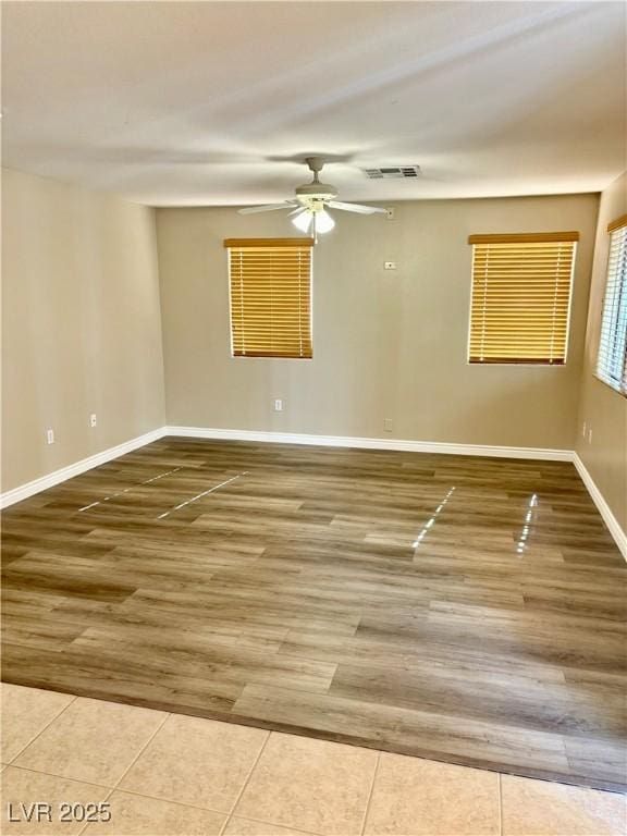 tiled empty room with ceiling fan and baseboards