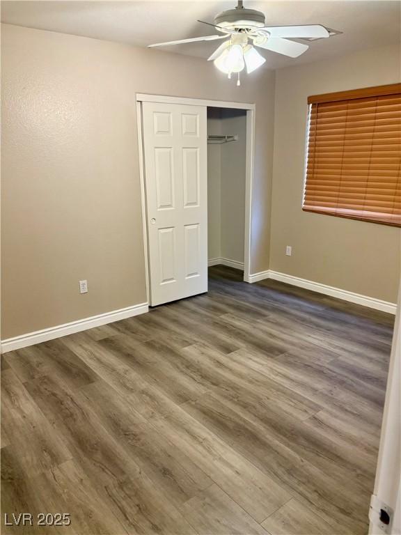 unfurnished bedroom featuring baseboards, a closet, dark wood-style floors, and ceiling fan