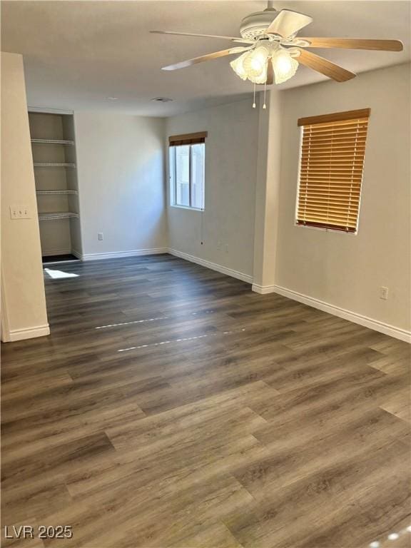 spare room featuring ceiling fan, baseboards, and dark wood-type flooring
