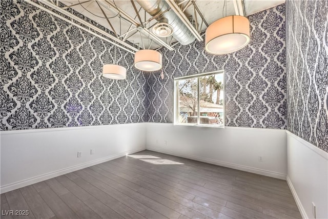empty room with wallpapered walls, wood finished floors, and baseboards