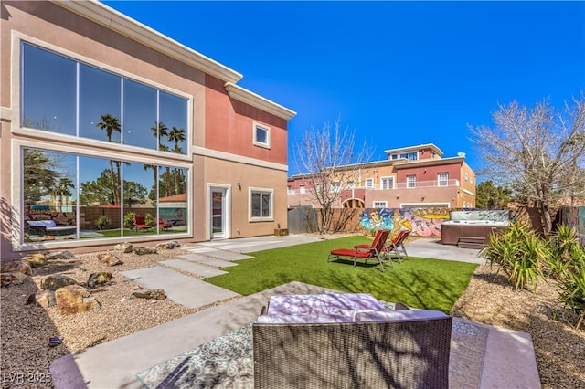 back of house featuring a hot tub, a patio area, and stucco siding