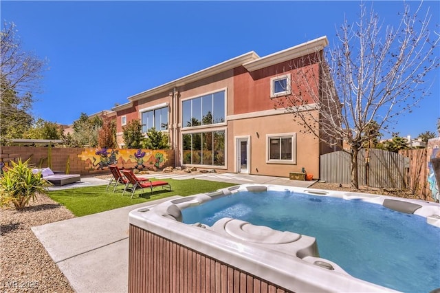 back of house featuring fence, a hot tub, and a patio area
