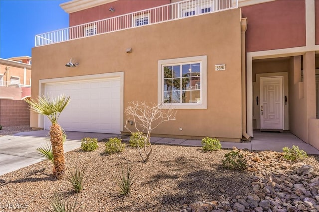 pueblo revival-style home featuring a garage, driveway, and stucco siding