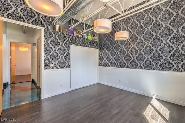 empty room featuring wallpapered walls, wood finished floors, and baseboards