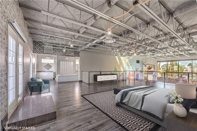 bedroom with a towering ceiling and wood finished floors