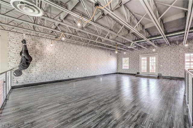 unfurnished living room featuring brick wall, wood finished floors, and baseboards