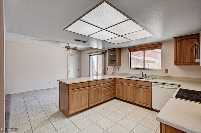 kitchen with dishwasher, a sink, a peninsula, light countertops, and a textured ceiling
