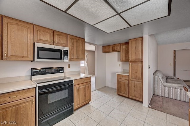 kitchen featuring range with electric cooktop, stainless steel microwave, light countertops, and light tile patterned floors