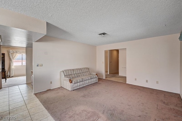 unfurnished room featuring light tile patterned floors, light colored carpet, and a textured ceiling