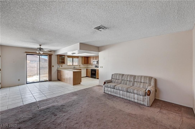 living area featuring light carpet, light tile patterned floors, ceiling fan, and a textured ceiling
