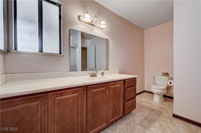 bathroom with toilet, vanity, tile patterned floors, and baseboards