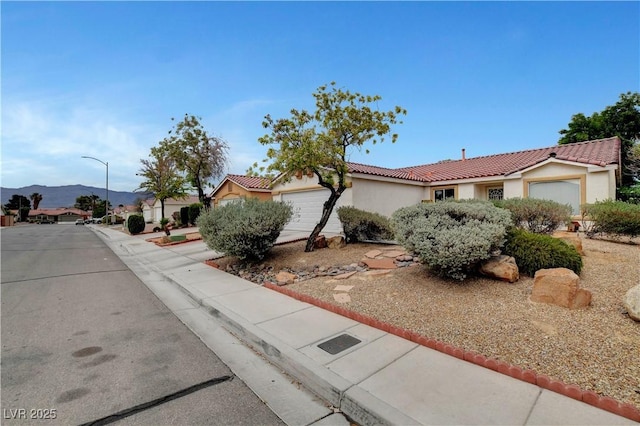 5220 Shasta Daisy St, North Las Vegas, NV 89031 - ranch-style home with a garage, a tiled roof, stucco siding, and a mountain view