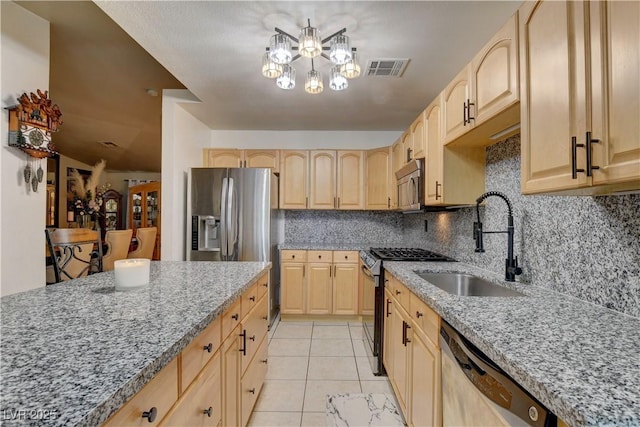 5220 Shasta Daisy St, North Las Vegas, NV 89031 - kitchen featuring stainless steel appliances, light brown cabinetry, a chandelier, and light stone counters
