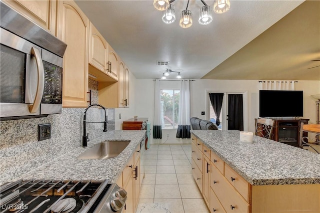 5220 Shasta Daisy St, North Las Vegas, NV 89031 - kitchen with stainless steel appliances, open floor plan, a sink, light brown cabinetry, and tasteful backsplash