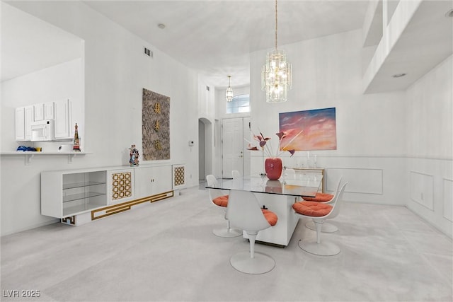 carpeted dining space featuring a chandelier and arched walkways