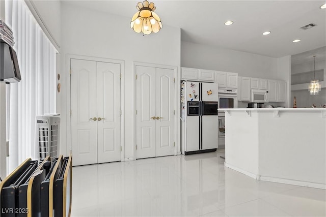 kitchen with white appliances, light tile patterned floors, recessed lighting, white cabinets, and decorative light fixtures