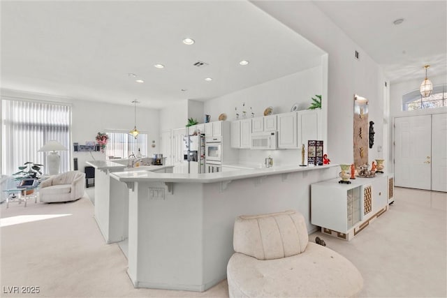 6141 Markleham Ave, Las Vegas, NV 89130 - kitchen featuring white appliances, recessed lighting, light countertops, a kitchen breakfast bar, and light colored carpet
