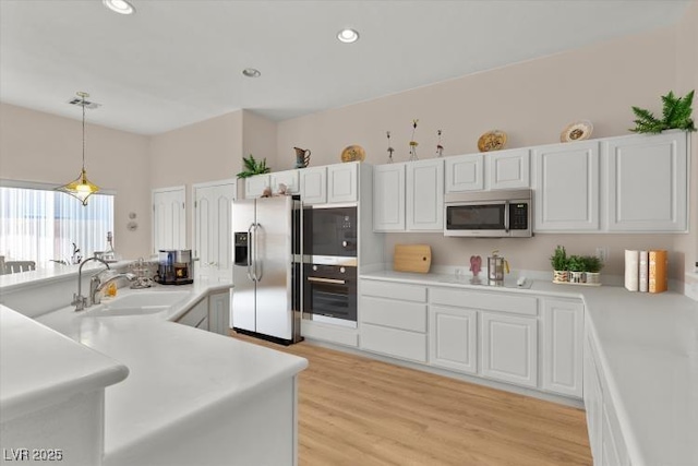 6141 Markleham Ave, Las Vegas, NV 89130 - kitchen with stainless steel appliances, light countertops, pendant lighting, white cabinetry, and light wood finished floors