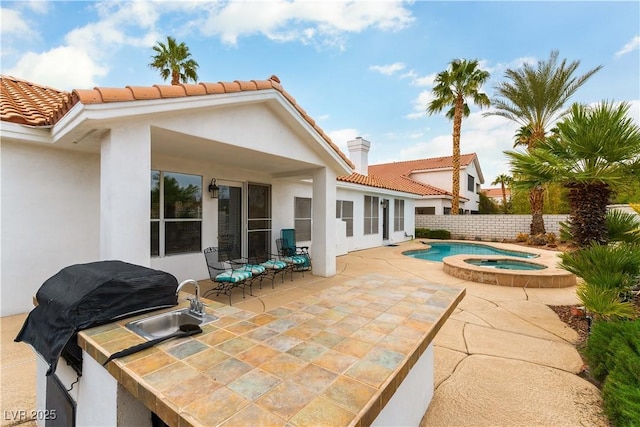 1933 Davina St, Henderson, NV 89074 - back of property featuring a sink, stucco siding, an outdoor kitchen, a tiled roof, and a patio area