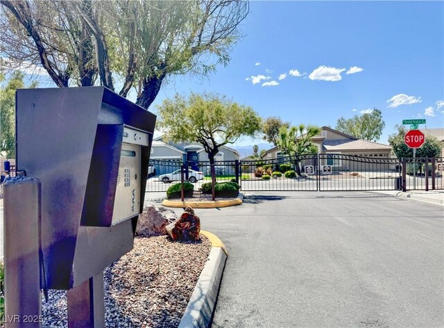 5422 Nestled Moon Ct, Las Vegas, NV 89131 - view of asphalt road with a gate, traffic signs, a gated entry, and curbs