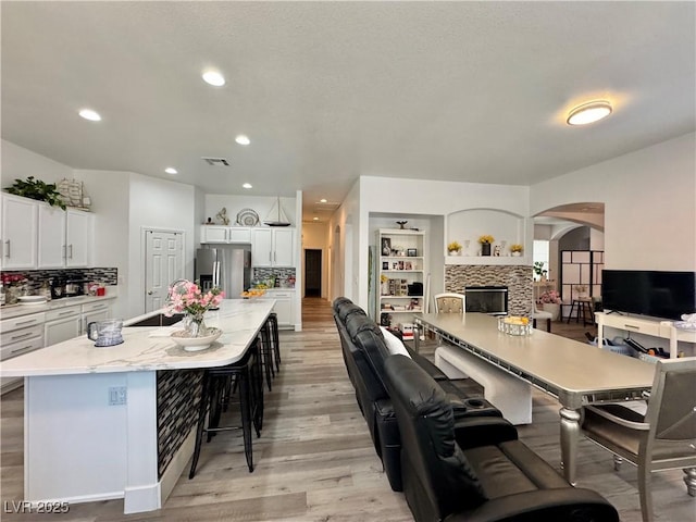 5422 Nestled Moon Ct, Las Vegas, NV 89131 - dining space featuring light wood-style flooring, arched walkways, a fireplace, and recessed lighting