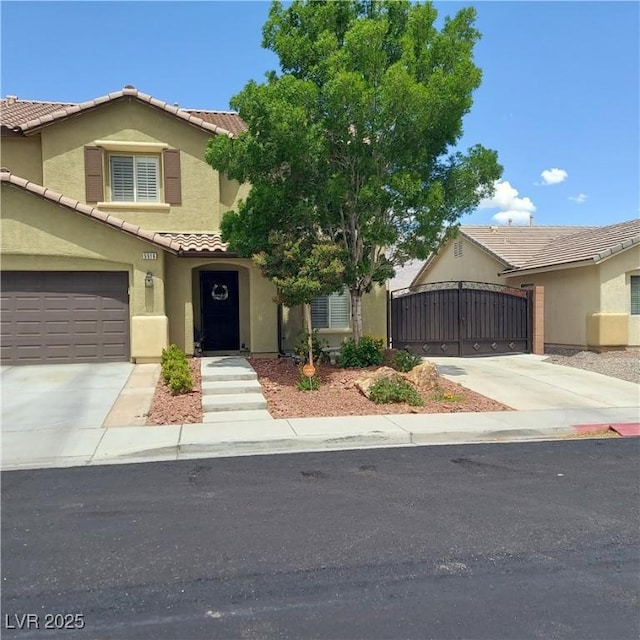 view of front of house with a tiled roof, stucco siding, concrete driveway, and a gate