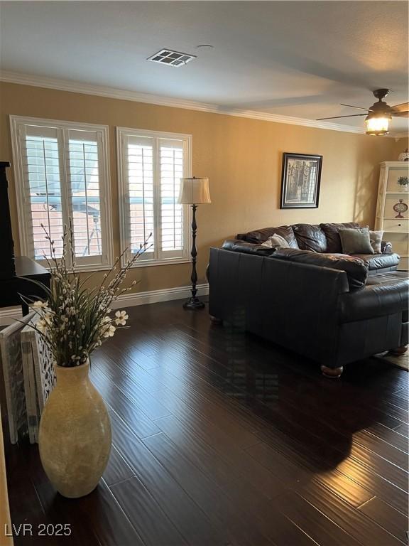 living area featuring baseboards, hardwood / wood-style flooring, crown molding, and a ceiling fan
