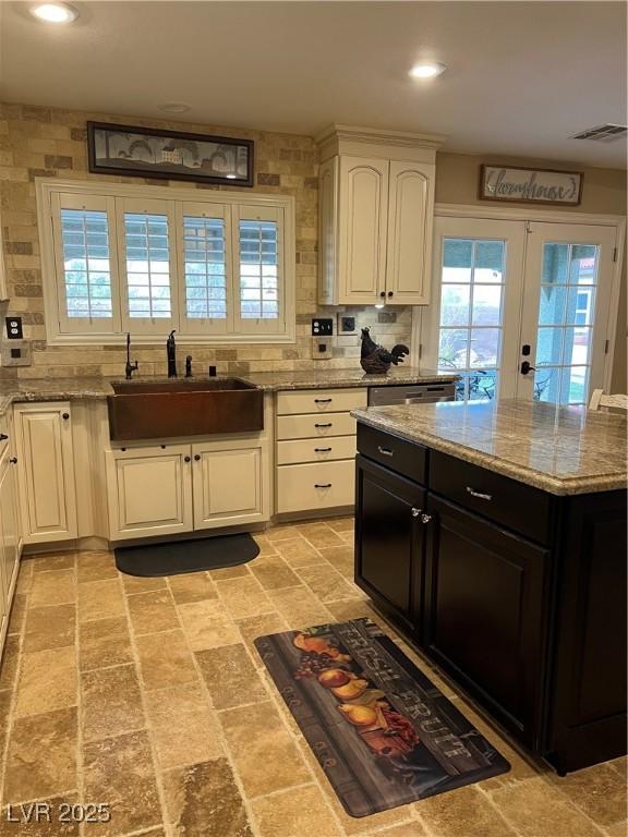 kitchen with a sink, french doors, white cabinets, tasteful backsplash, and recessed lighting
