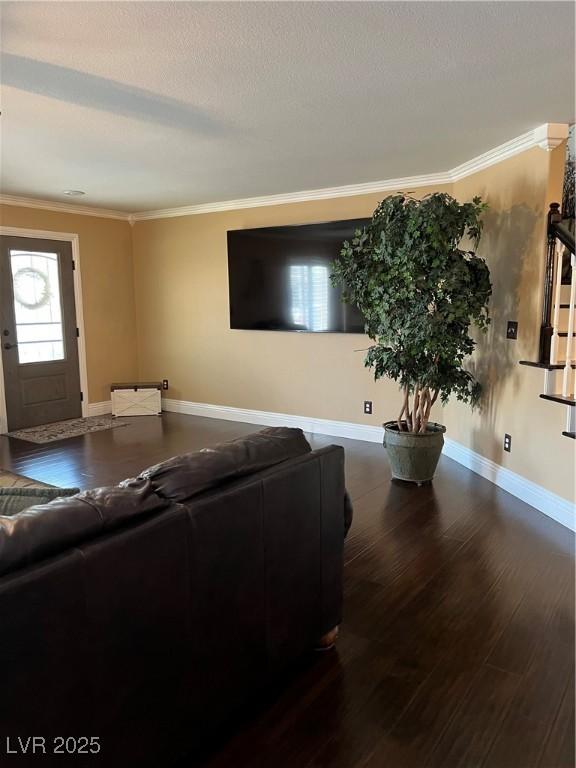 living area featuring crown molding, wood finished floors, baseboards, and a textured ceiling