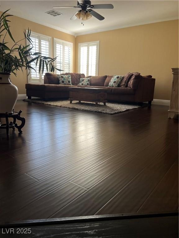 living room featuring ceiling fan, baseboards, ornamental molding, and dark wood-style flooring