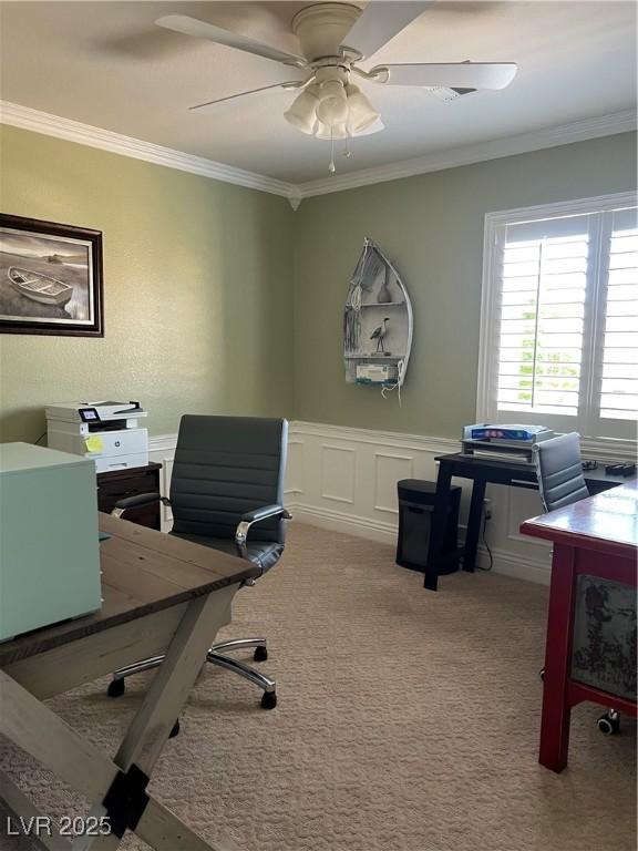 office area featuring crown molding, a ceiling fan, a wainscoted wall, and carpet flooring
