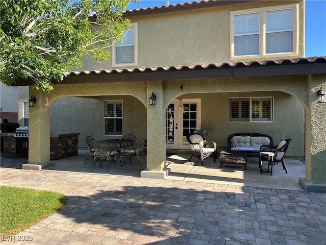 rear view of house featuring stucco siding, a patio, and an outdoor living space