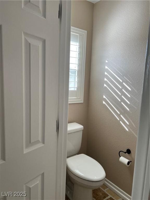 bathroom featuring toilet and baseboards
