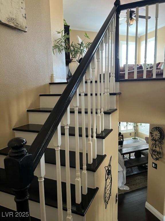 staircase with healthy amount of natural light, wood finished floors, and baseboards