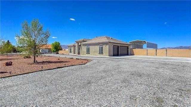 3780 Shawnee Ave, Pahrump, NV 89048 - view of front facade featuring fence, gravel driveway, an attached garage, a carport, and stucco siding