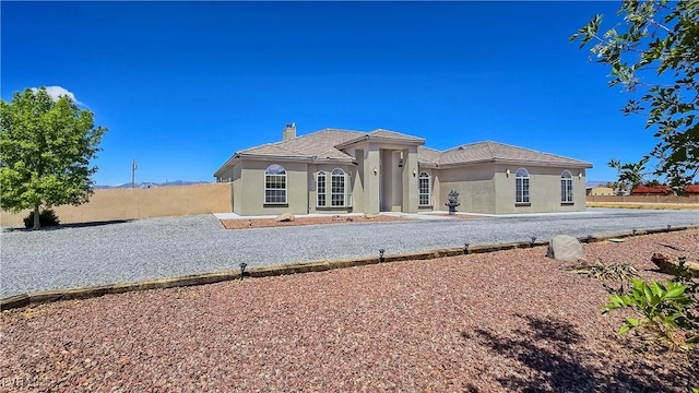 3780 Shawnee Ave, Pahrump, NV 89048 - back of house featuring fence, a chimney, stucco siding, and a tile roof