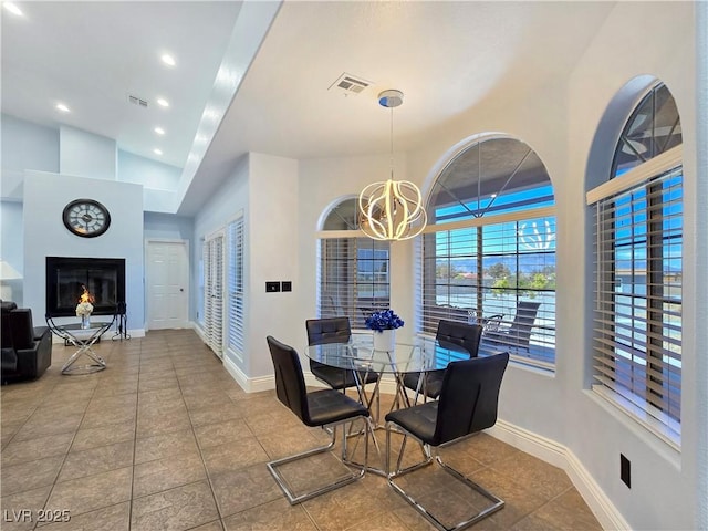 3780 Shawnee Ave, Pahrump, NV 89048 - dining area featuring a chandelier, a glass covered fireplace, tile patterned flooring, vaulted ceiling, and baseboards