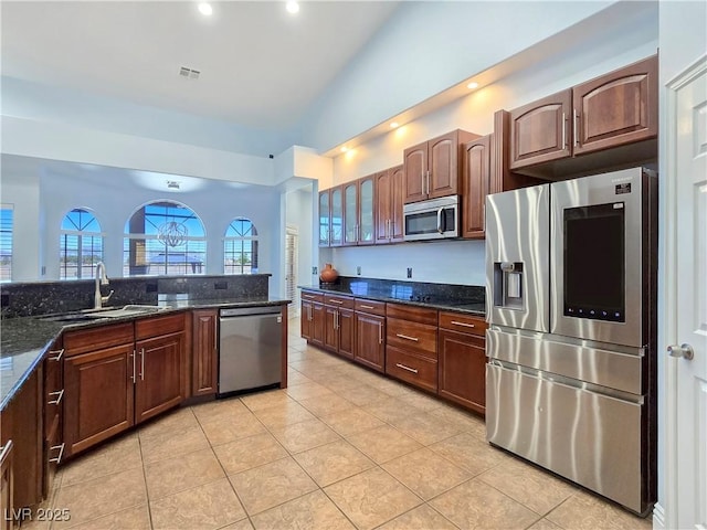 3780 Shawnee Ave, Pahrump, NV 89048 - kitchen featuring stainless steel appliances, a sink, light tile patterned floors, dark stone counters, and vaulted ceiling
