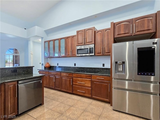 3780 Shawnee Ave, Pahrump, NV 89048 - kitchen featuring appliances with stainless steel finishes, light tile patterned floors, dark stone counters, and glass insert cabinets