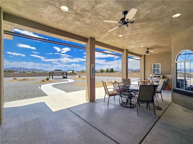 3780 Shawnee Ave, Pahrump, NV 89048 - view of patio with outdoor dining space, a ceiling fan, a gazebo, a fenced backyard, and a water and mountain view