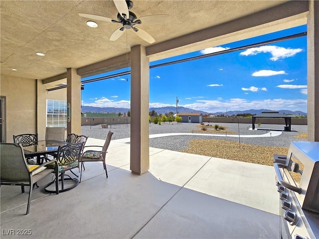 3780 Shawnee Ave, Pahrump, NV 89048 - view of patio / terrace featuring a mountain view, a ceiling fan, a grill, outdoor dining space, and a fenced backyard