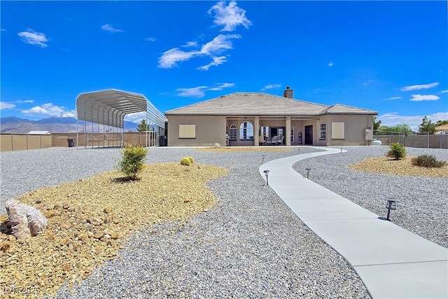 3780 Shawnee Ave, Pahrump, NV 89048 - view of front of home with fence, a carport, a chimney, and stucco siding
