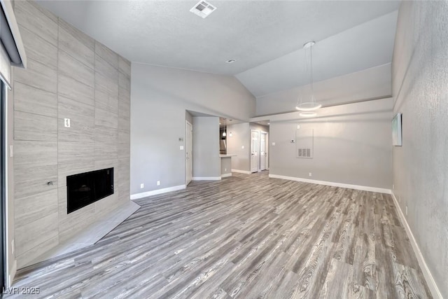 unfurnished living room with vaulted ceiling, wood finished floors, a fireplace, and baseboards